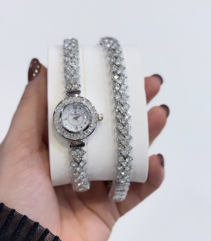 Relógio feminino prateado cravejado ao lado de pulseira combinando