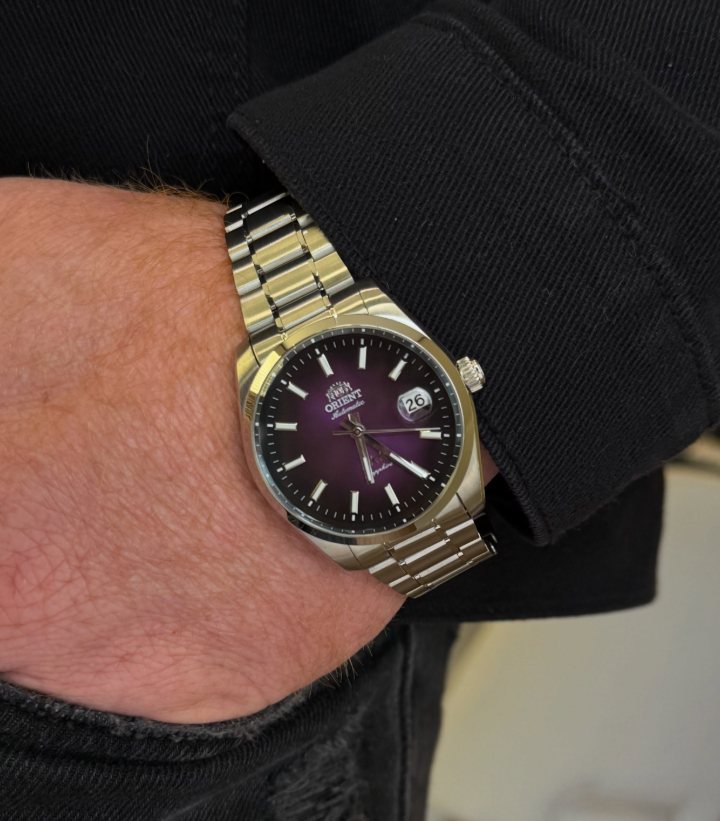Relógio Orient automático com mostrador roxo e pulseira de aço, no pulso