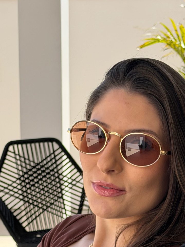 Cliente com óculos de sol redondo de aro dourado e lentes marrons